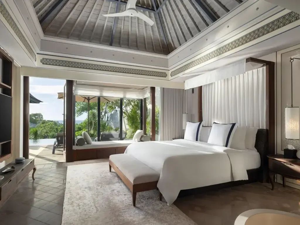 Luxuriöses Schlafzimmer mit großem Bett und Blick auf den Garten durch große Fenster