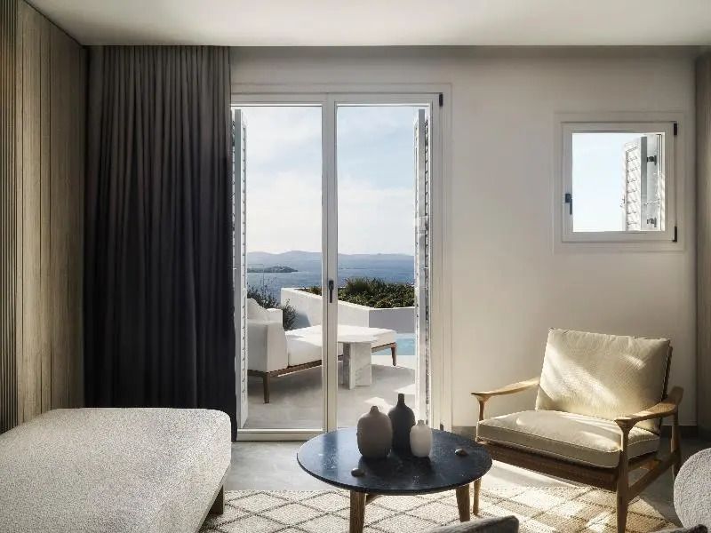 Helle Suite mit Sitzbereich und Blick auf das Meer vom Balkon des Deos Mykonos.