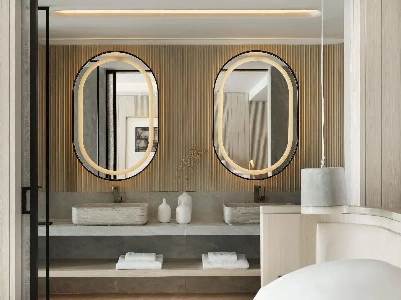 Elegantes Badezimmer mit Doppelwaschbecken und ovalen Spiegeln im Deos Mykonos.