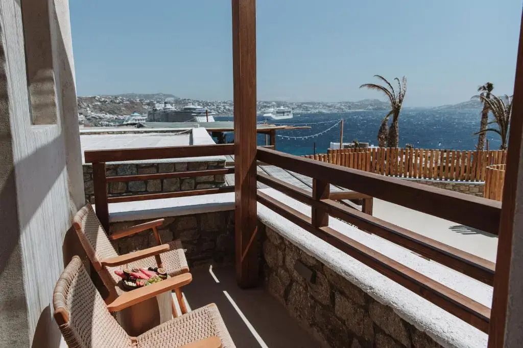 Balkon mit Holzstühlen, Blick auf das Meer und die Küste von Mykonos