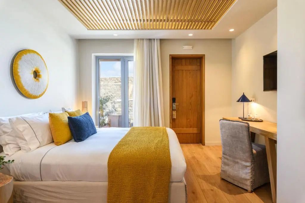 Helles Doppelzimmer mit gelben und blauen Kissen und Holzelementen