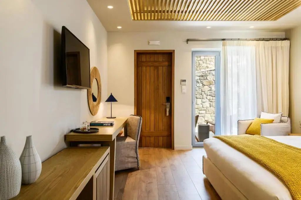 Zimmeransicht mit Schreibtisch und Wand-TV neben der Holztür