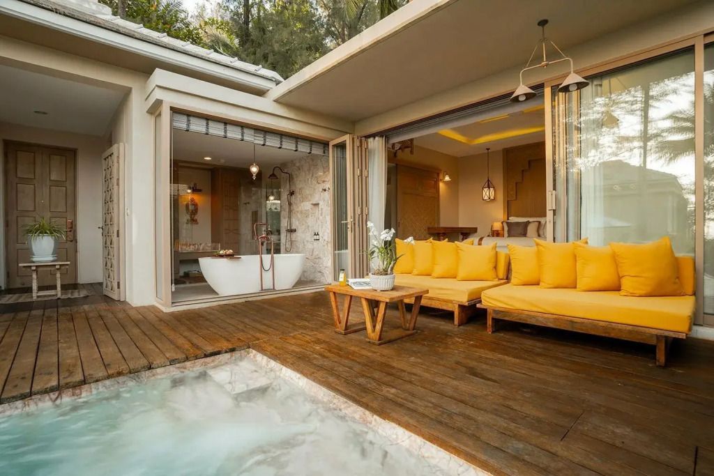 Poolterrasse mit bequemen gelben Sitzecken und Zugang zur Villa.
