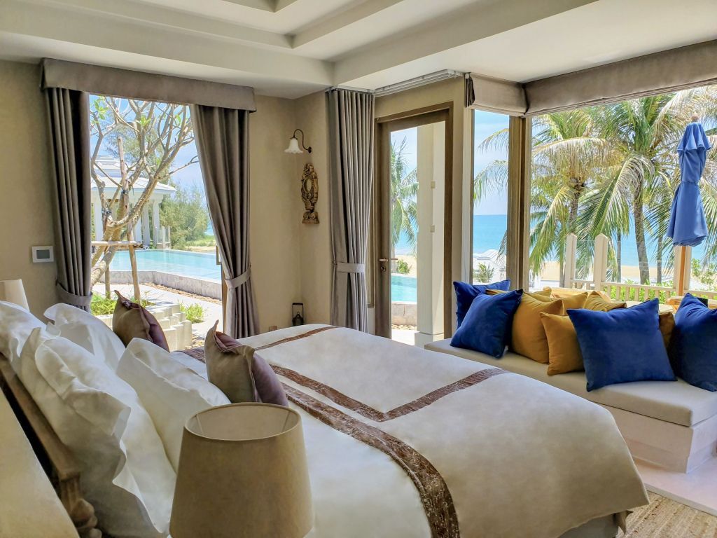 Luxuriöses Schlafzimmer mit Blick auf den Pool und das Meer durch große Fenster.