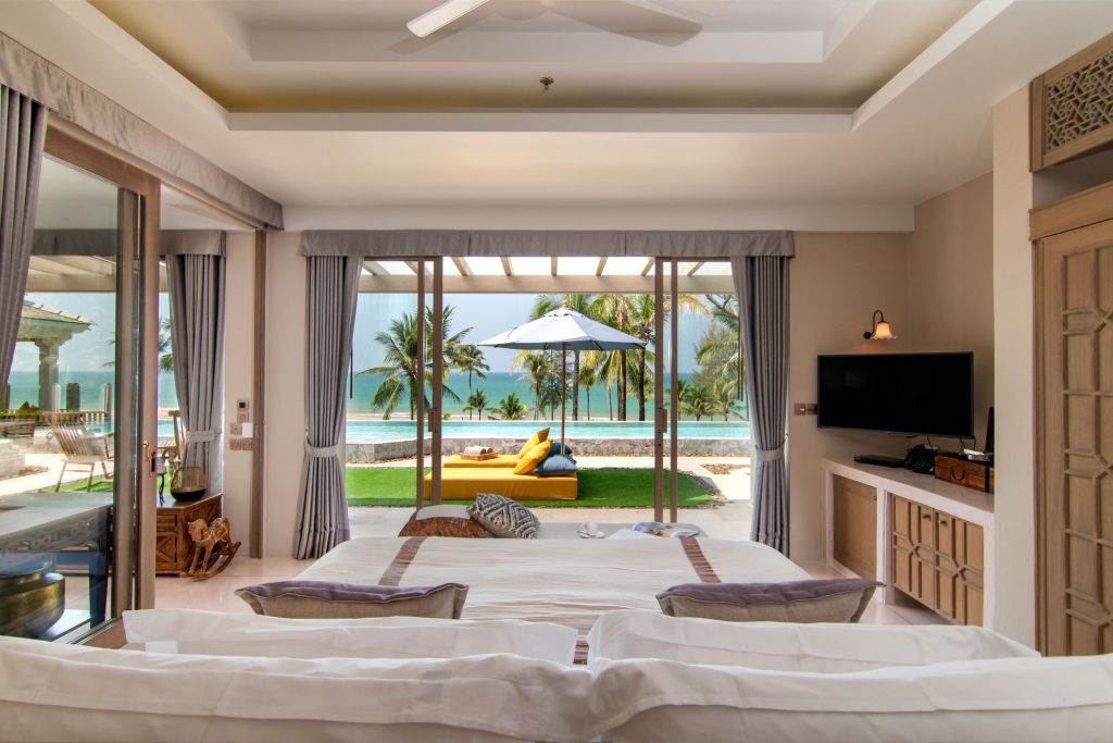Großzügiges Zimmer mit Blick auf den Pool und das Meer durch Schiebetüren.