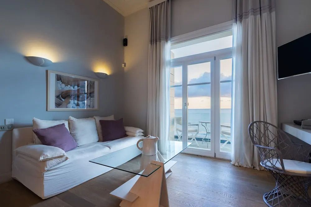 Gemütliche Suite mit Sofa und Balkon mit Blick auf Sonnenuntergang