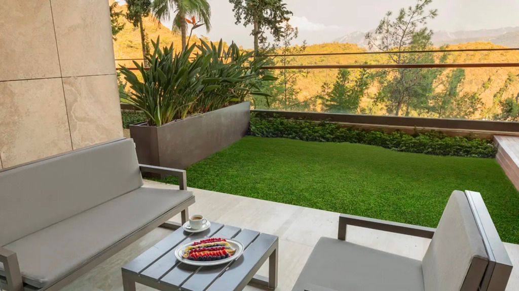 Private Terrasse eines Deluxe Zimmers mit Blick auf grüne Hügel und Palmen