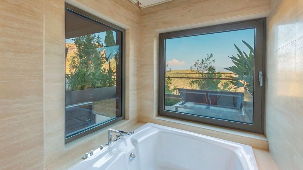 Aussicht vom Whirlpool im Badezimmer auf die Gartenlandschaft und Berge