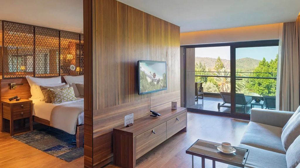 Junior-Suite mit moderner Holzeinrichtung und Blick auf den Balkon. Helles Raumdesign.