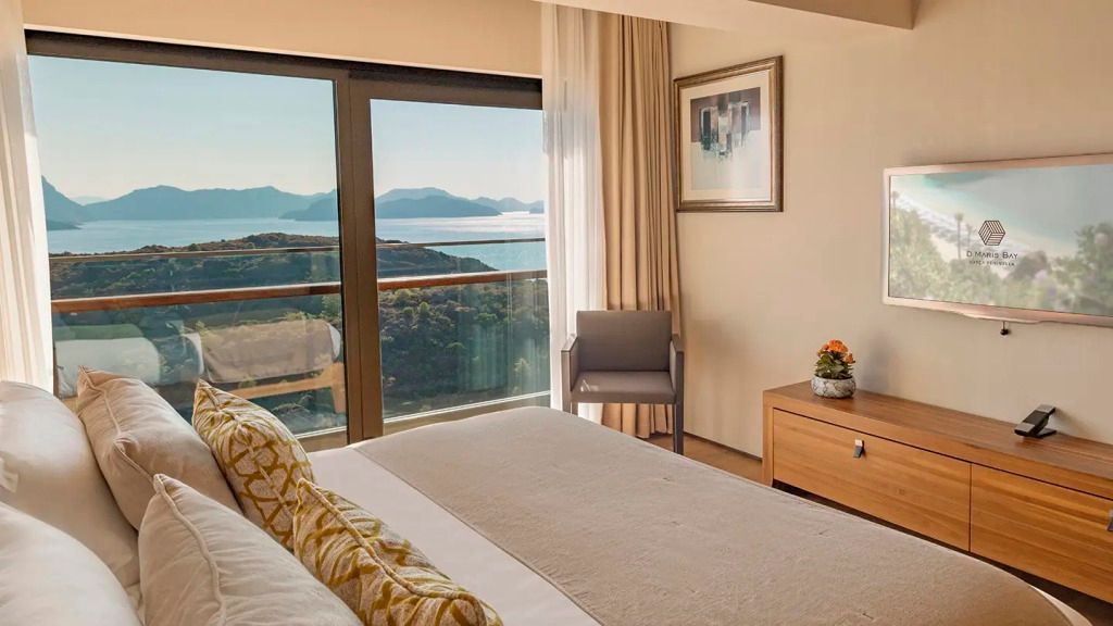 Hotelzimmer mit Doppelbett und großer Fensterfront mit Blick auf die Küste