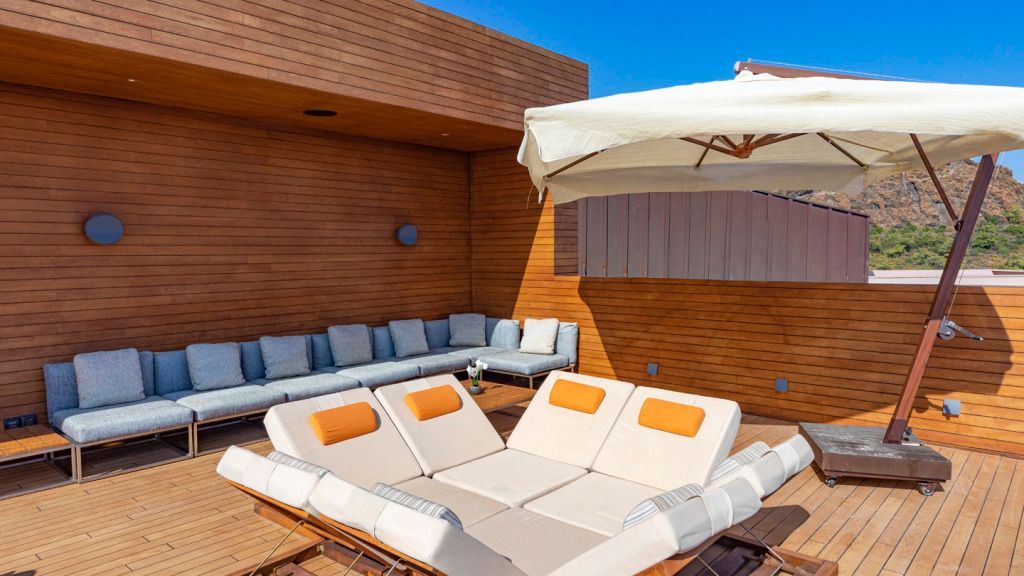 Moderne Dachterrasse mit Liegen und Sonnenschirm aus Holz gestaltet