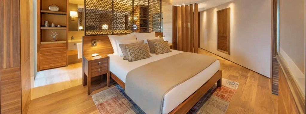 Blick auf ein elegantes Bett in einer Superior Suite mit stilvollem Holzmöbel