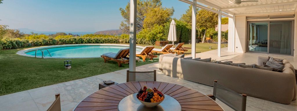 Terrasse mit Sitzbereich und Blick auf den Pool und die umgebende Natur
