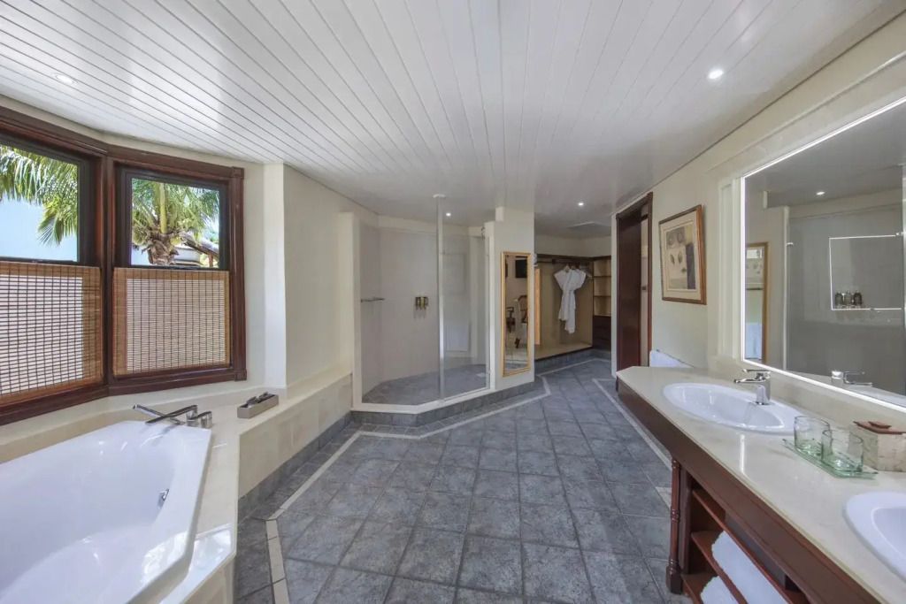 Großes Badezimmer mit Badewanne, Dusche und zwei Waschbecken, moderne Einrichtung.