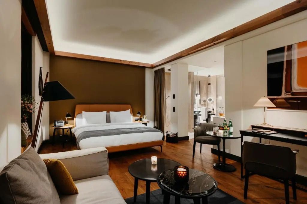 Elegante Junior-Suite mit Doppelbett, Sitzbereich und warmem Licht.