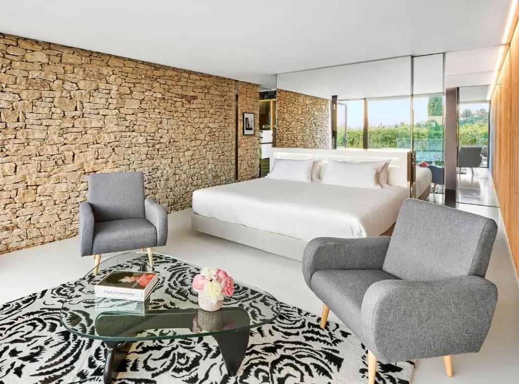 Gemütliches Schlafzimmer mit Natursteinwand und modernen Sesseln in der Junior-Suite