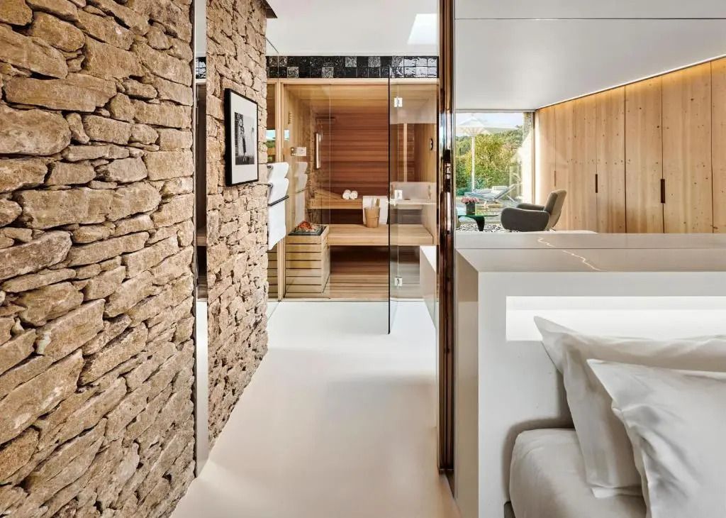 Suite mit Naturstein- und Holzelementen sowie Sauna im Hintergrund