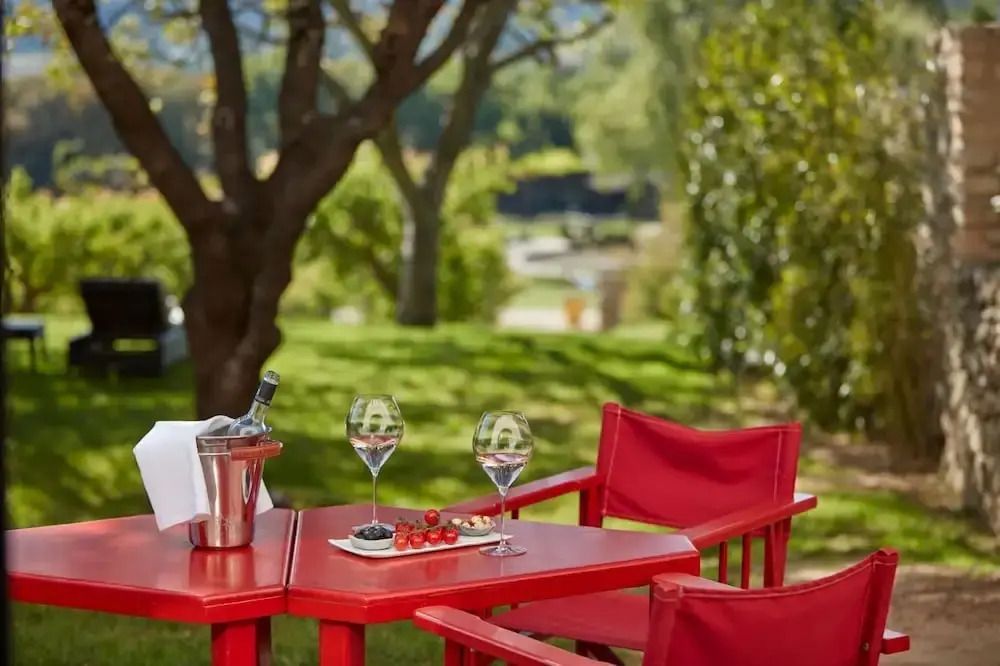 Gartenbereich mit rotem Tisch Stühlen und Wein vor malerischer Kulisse
