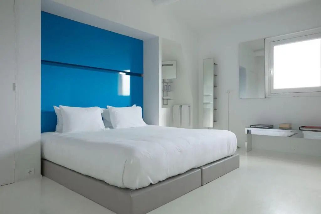 Helles Schlafzimmer mit großem Doppelbett und blauer Akzentwand