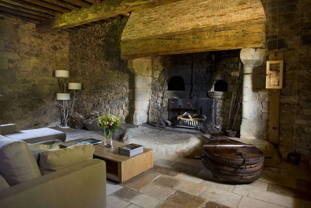 Steinkamin in rustikalem Wohnzimmer mit Holzdecke und Blumenarrangement