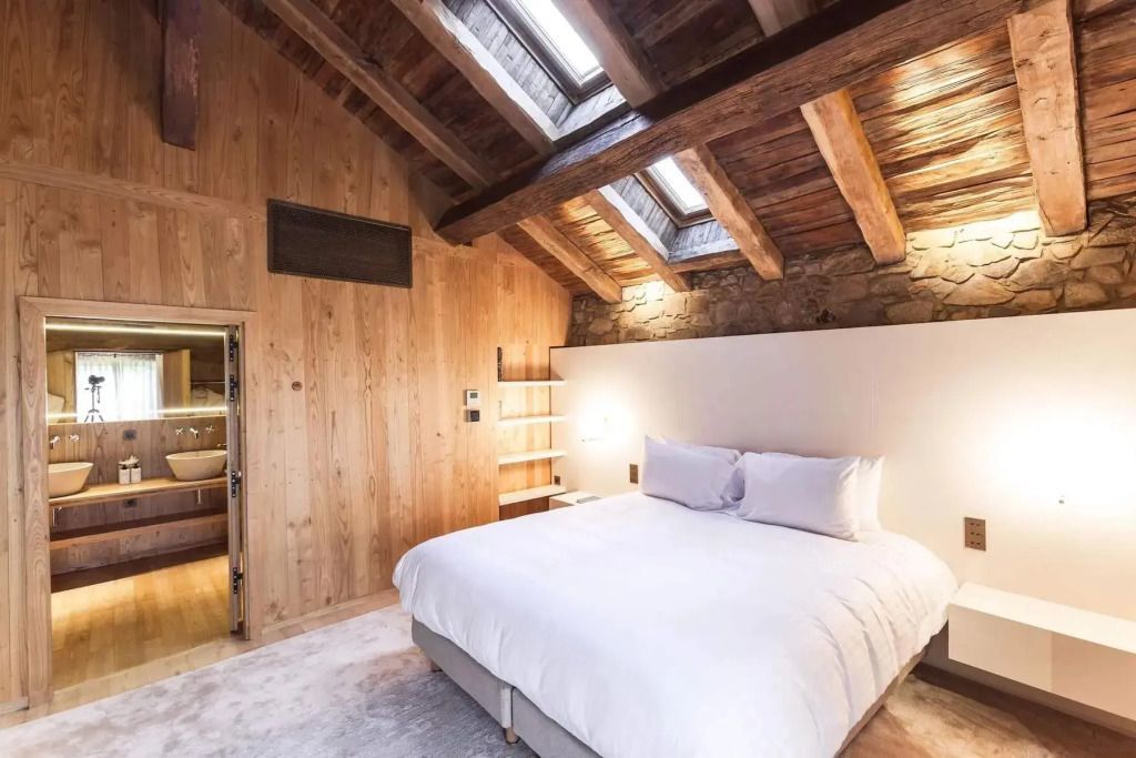 Helles Schlafzimmer mit Holzbalkendecke und einem großen Doppelbett