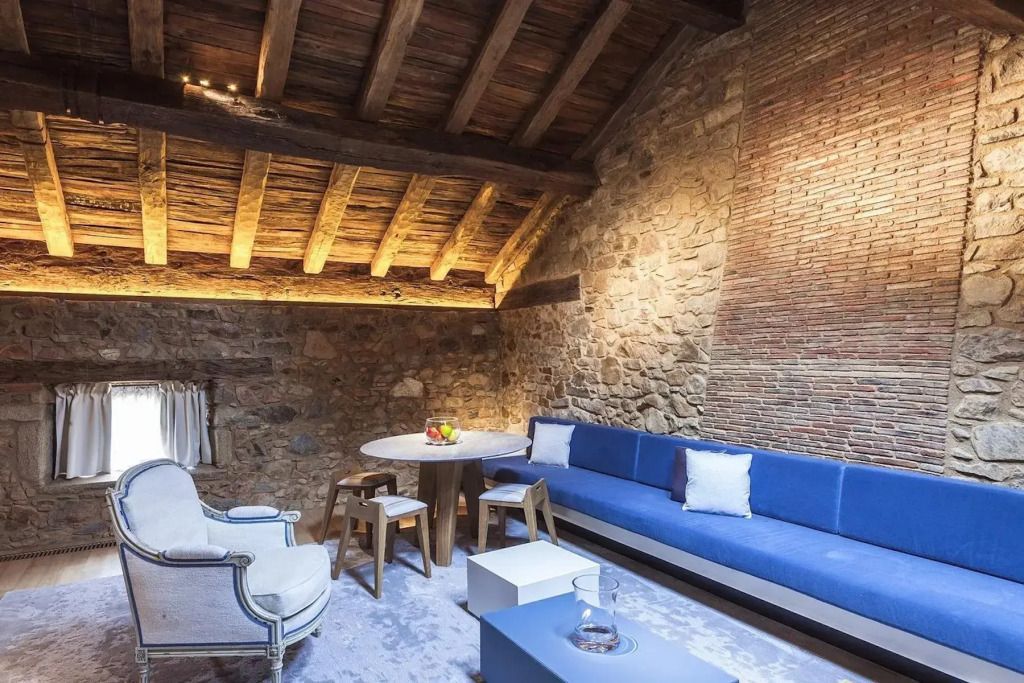 Gemütliche Lounge mit Steinmauer und blauen Polstermöbeln in rustikalem Ambiente