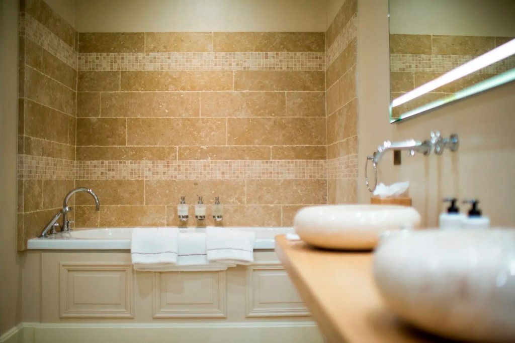 Stilvolles Badezimmer mit großer Badewanne und Natursteinfliesen