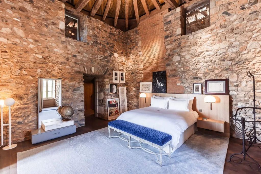 Luxuriöses Schlafzimmer mit rustikalen Steinwänden und elegantem Doppelbett.