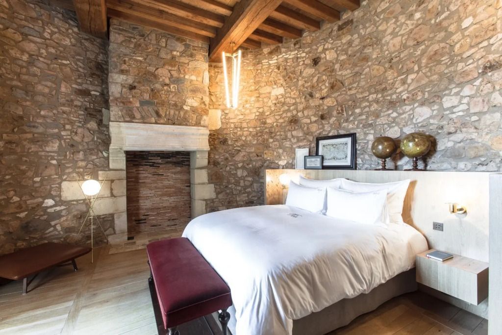 Rustikales Zimmer mit Steinmauern, großem Doppelbett und Kamin im Domaine des Etangs
