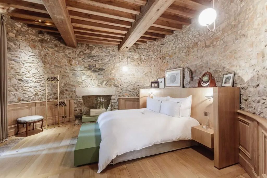 Elegantes Schlafzimmer mit Steinwänden und Holzbalkendecke im Mercure Prestige Doppelzimmer.