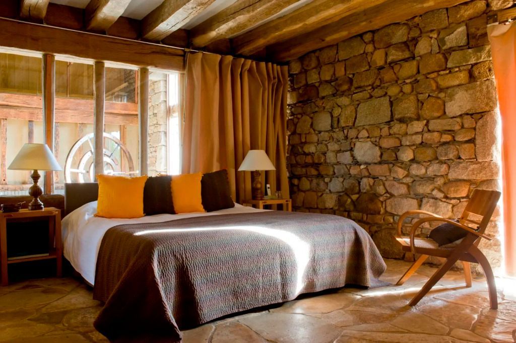 Gemütliches Schlafzimmer mit Natursteinwänden und rustikalen Holzbalken
