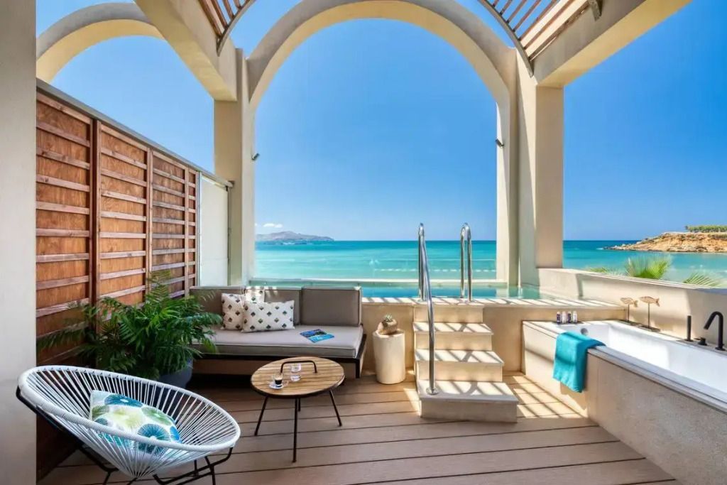Terrasse mit Meerblick, Sitzgelegenheiten und privatem Jacuzzi in luxuriöser Umgebung.