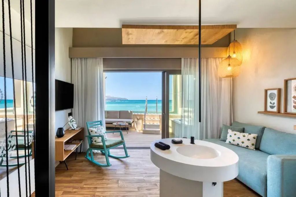 Helles Zimmer mit Zugang zur Terrasse und Ausblick auf das Meer in einer modernen Suite.