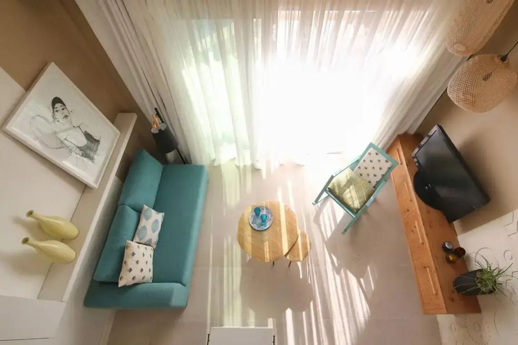 Helles Wohnzimmer mit blauem Sofa und weißen Vorhängen.