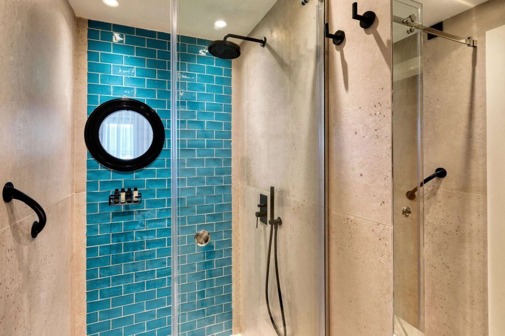 Moderne Dusche mit türkisfarbiger Fliesenwand und Regendusche.