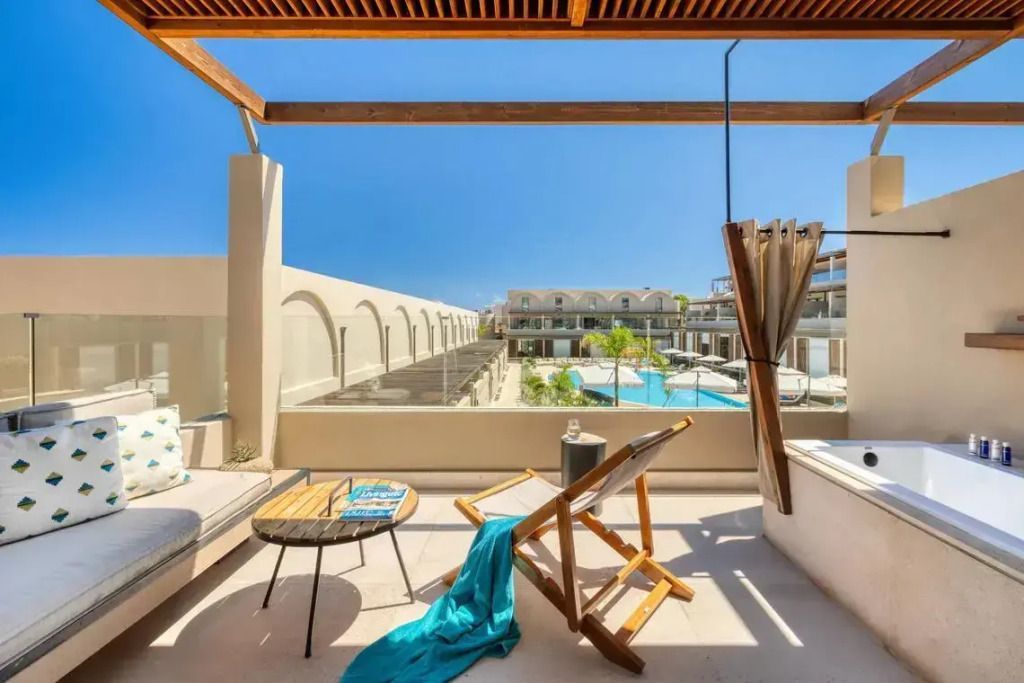 Terrasse mit Liegestühlen und Blick auf den Poolbereich im Domes Noruz Chania.