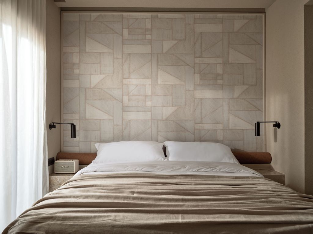 Gemütliches Doppelbett mit stilvoller Kopfteilbeleuchtung und geometrischem Wandmuster