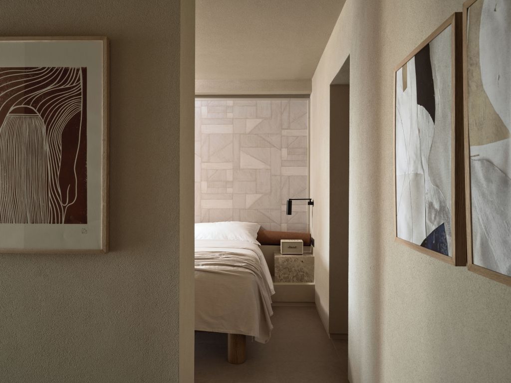 Blick in ein modernes Schlafzimmer durch einen Flur mit geschmackvollen Kunstwerken
