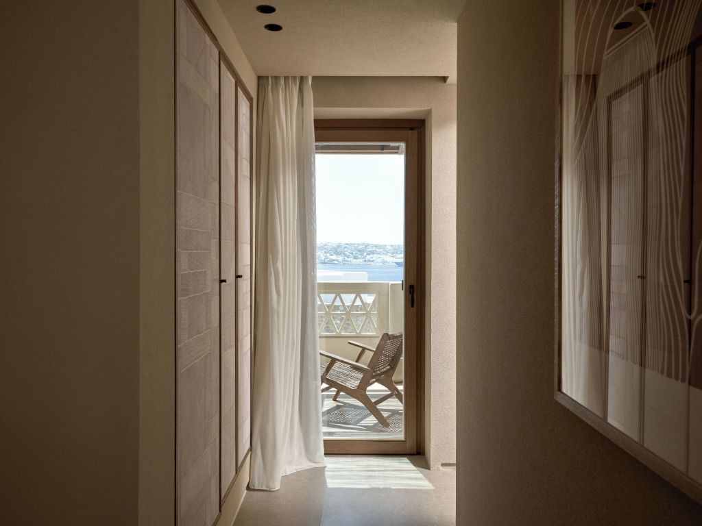 Heller Gang führt zu einem Balkon mit Blick auf das Meer und stilvollem Sitzbereich
