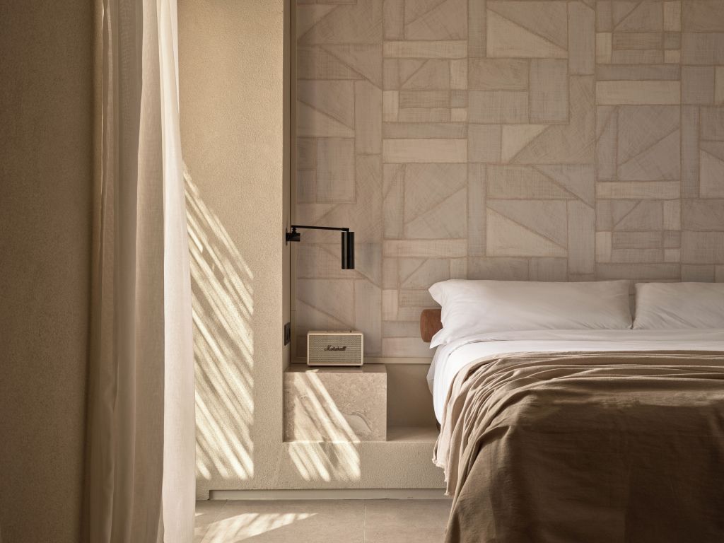 Sonnendurchflutetes Bett mit geometrischem Wandmuster im Doppelzimmer.