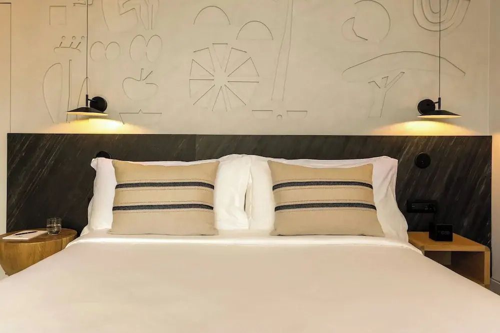 Gemütliches Doppelbett mit dekorativen Kissen und künstlerischer Wandgestaltung