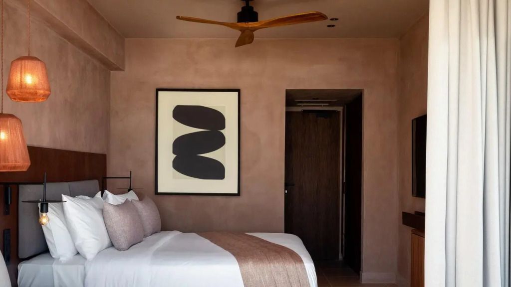 Geräumiges Hotelzimmer mit Doppelbett, stilvolle Kunst an der Wand, moderne Einrichtung.