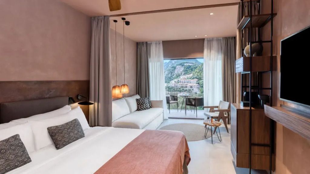 Moderne Suite mit Doppelbett, Sofa, Balkon und Ausblick auf die Natur. Elegante Beleuchtung.