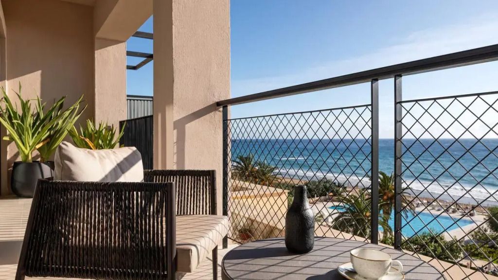 Terrasse mit Tisch und Vase, im Hintergrund Blick auf Pool und Meer