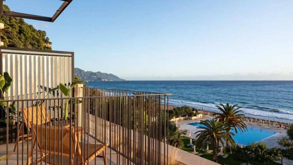 Balkonblick auf das Meer und die Anlage mit Palmen und Pool