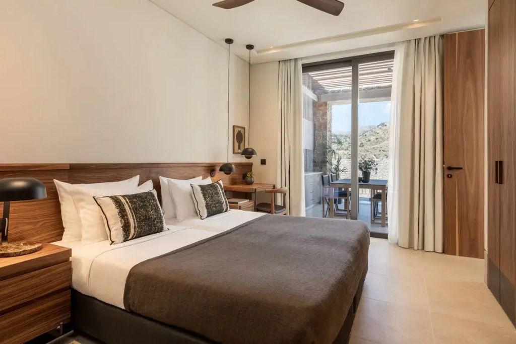 Schlafzimmer mit Doppelbett und Zugang zur Terrasse in moderner Einrichtung