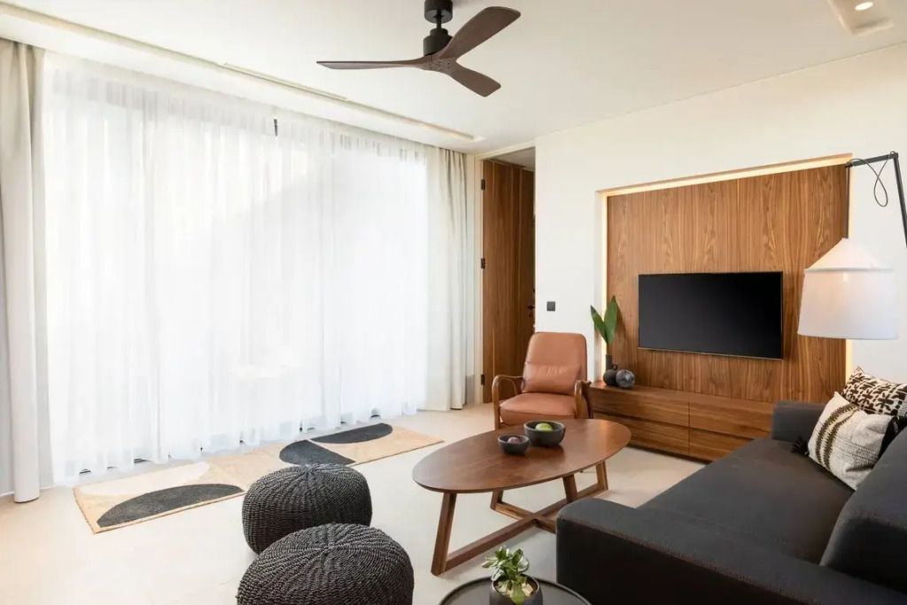Wohnbereich mit Sofa, Tisch und moderner Einrichtung vor einem Fenster