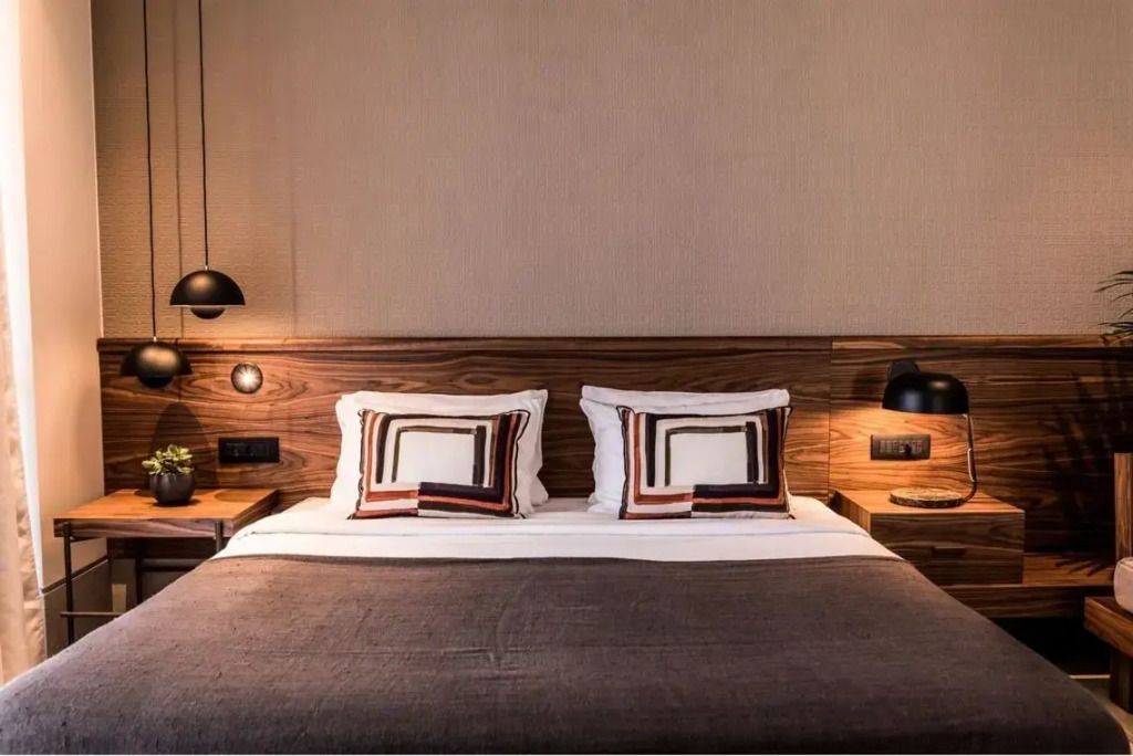 Gemütliches Doppelbett mit dekorativen Kissen und Holzverkleidung an der Wand