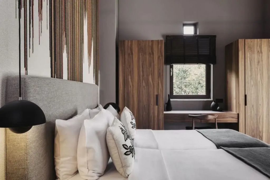 Doppelbett mit Zierkissen, großer Fensterblick und Holzelementen.