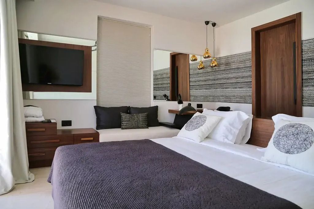 Modernes Schlafzimmer mit Doppelbett, stilvollen Lampen und Flachbildfernseher